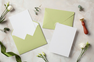 Wedding stationery set. Flat lay olive envelopes, blank wedding invitation card, flowers on marble background.