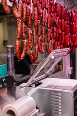 vertical portrait Vacuum Sealing Machine in Butcher Shop with Chorizos Hanging in Foreground
