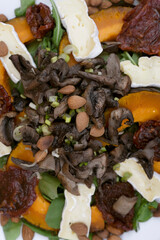 Healthy food and nutrition. Top view of a gourmet salad with arugula, roasted pumpkin, almonds, brie cheese, sun dried tomatoes and mushrooms.	
