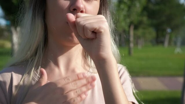 Teen coughing in green nature. A young girl coughing because of flowers allergy in nature.
