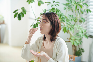 ベッドでサプリを飲む20代女性