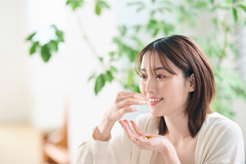 ベッドでサプリを飲む20代女性
