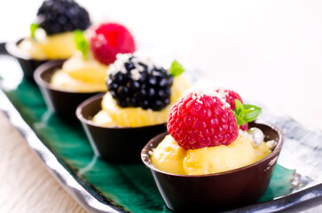 Traditional German chocolate pralines with vanilla pudding and fruits in a chocolate bowl