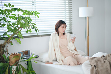 ベッドでスマートフォンを見る20代女性