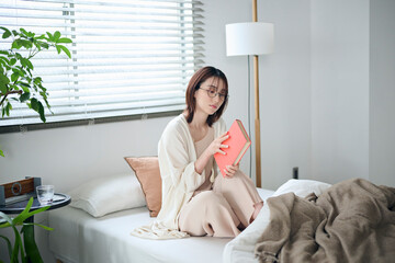 ベッドで本を読む20代女性