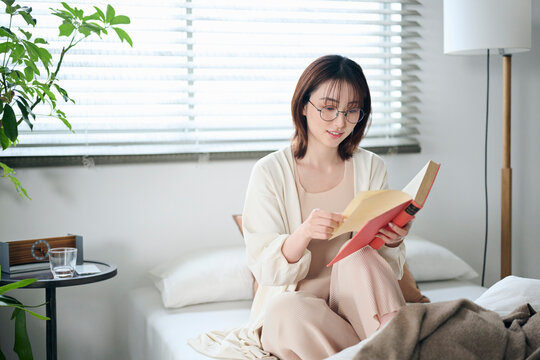 ベッドで本を読む20代女性