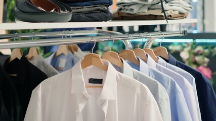 Panning shot of stylish formal clothes on hanger in empty fancy fashion boutique. Latest exquisite...
