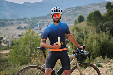 Man cyclist holding a banana with a background of a blue cycling jersey. Healthy nutrition of a...