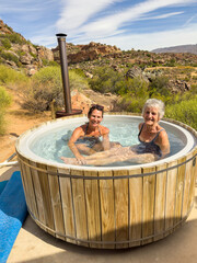 Vleiplaas Clanwilliam Cederberg South Africa. 14/02/2024. Women campers enjoying the wood fired hot tub in the open air.