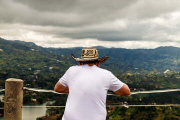 Man seen from behind observes the Peñon-Guatape reservoir in Antioquia, Colombia