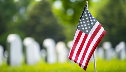 A small American flag is prominently displayed in the foreground with numerous uniform white headstones, indicative of a military cemetery, blurred in the background