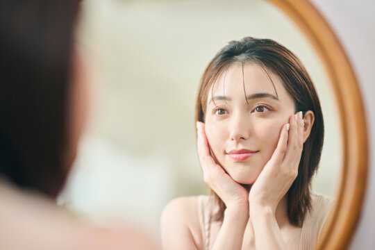 鏡に映るスキンケアをする20代女性
