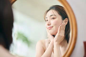 鏡に映るスキンケアをする20代女性