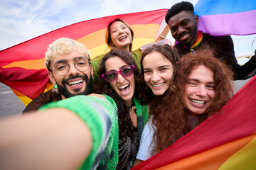 A crowd of happy people in colorful smile for a selfie with a rainbow flag, capturing their fun and leisurely travel recreation. Gay and lesbian friends together in the gay pride parade. LGBT concept