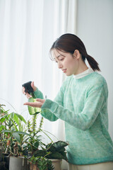 観葉植物の世話をする20代女性