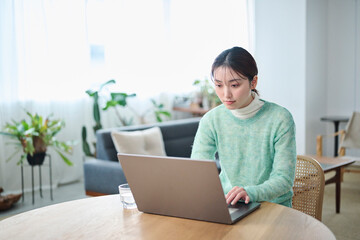 リビングでパソコンでの作業をする20代女性
