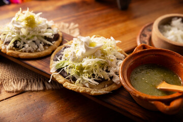 Sope. Traditional homemade Mexican food prepared with flattened and pinched on the border fried corn dough covered with refried beans, green or red sauce, lettuce, cheese, onion and sour cream. - 763626953