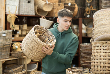 Male shopper in furniture center chooses a new wicker laundry basket