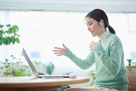 リビングでオンラインミーティングをする20代女性