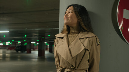 Frightened Asian ethnic chinese korean woman hiding from danger pursuit threat phobia in underground shelter night dark car parking scared fearful girl stand alone near stop driving traffic road sign