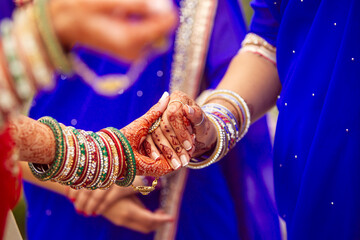 Bridesmaid holds Indian bride henna tattoo hand before wedding ceremony