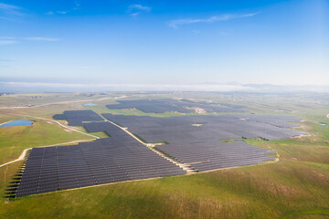A large field of solar panels is spread across the landscape