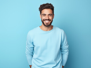 Hombre latino, joven, atractivo y con barba corta, feliz, usando ropa casual de color azul posando sobre un fondo del mismo color