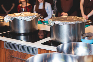 Group of guests in a cooking class studio, adults preparing different dishes in the kitchen...