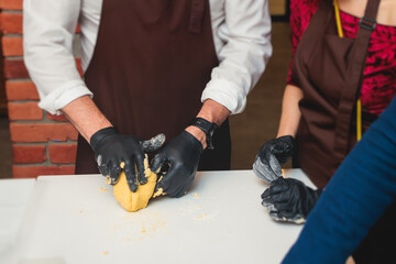 Group of guests in a cooking class studio, adults preparing different dishes in the kitchen...
