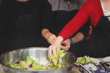 Group of people in a cooking class studio, adults preparing different dishes in the kitchen together, people in aprons learn on culinary master class, chef uniform, hands in gloves, italian cuisine