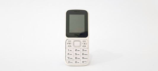 White old handphone on white background. This phone has a classic design before the smartphone era	

