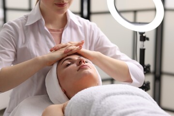 Cosmetologist making face massage to client in clinic, closeup