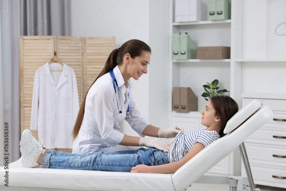 Poster Gastroenterologist examining girl with stomach ache on couch in clinic