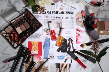Bright lip glosses among different cosmetic products and fashion magazine on table, flat lay - obrazy, fototapety, plakaty