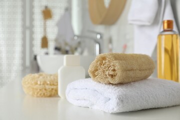 Fototapeta na wymiar Natural loofah sponge and towel on table in bathroom. Space for text