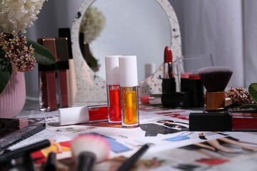 Bright lip glosses among different cosmetic products and fashion magazine on table indoors - obrazy, fototapety, plakaty