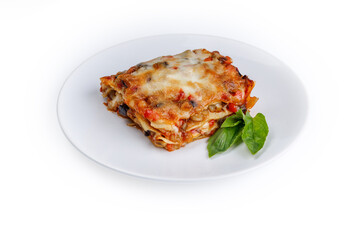plate of lasagna with green basil on white background