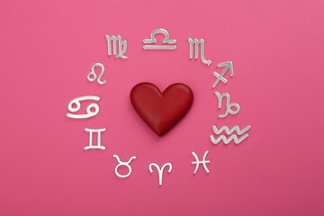 Zodiac signs and red heart on pink background, flat lay