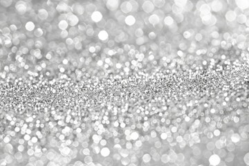 Ethereal white bokeh lights shimmer across a bed of silver glitter, perfect for holiday themes.