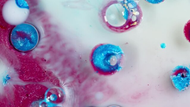 Vibrant ink droplets diffusing in water, creating abstract swirls of pink and blue, macro shot