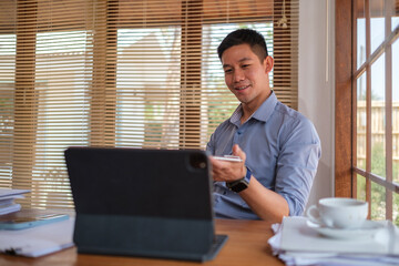 Handsome millennial businessman watching online webinar, working with digital tablet in office.