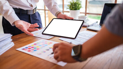 Creative designer or developer team using digital tablet working together on mobile app template design at co working space.