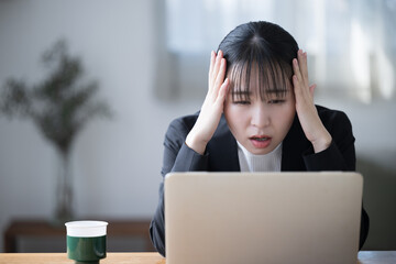 Fototapeta premium Woman with head in front of computer Images of headaches, work problems, failures, mistakes, investments, etc.