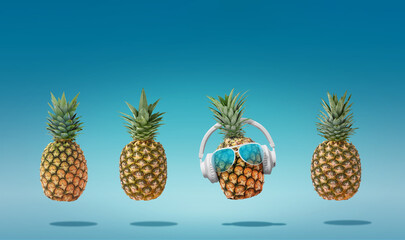Summer minimalist pop art composition made with 4 pineapples wearing headphones and listening to music.Minimal concept summer and party.Celebrating the summer vibes.Creative art.Contemporary style.