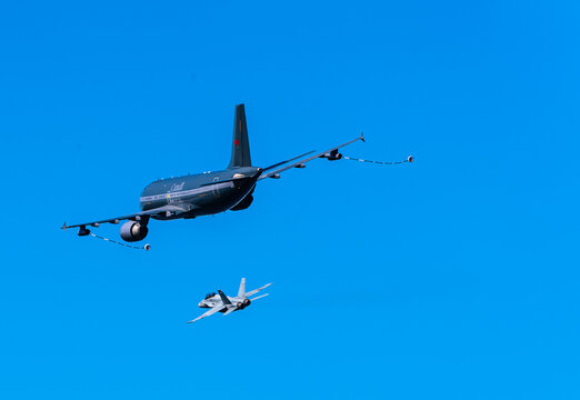 A Canadian CF-18 Hornet jet fighter being refueled in mid air by a CC-150 Polaris aircraft during an air show commemorating the victory at the Battle of Britain during World War II.