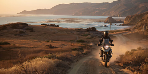 A man is riding a motorcycle on a dirt road near the ocean