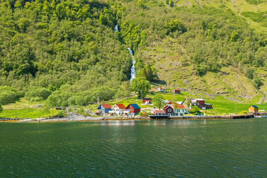 Cruising down the Nærøyfjord arm of the sognefjorden fjord passing a small village Tufte with wafterfall Tuftefossen