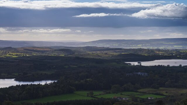 Time lapse of rural landscape with Kilronan castle in the distance surrounded by lake, forest and hills during a cloudy day viewed from above Lough Meelagh in county Roscommon in Ireland.
