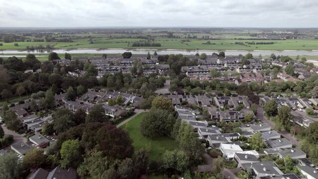 Backwards movement aerial reveal of shopping mal car parking lot in Dutch residential neighbourhood. City planning, infrastructure and urban development seen from above