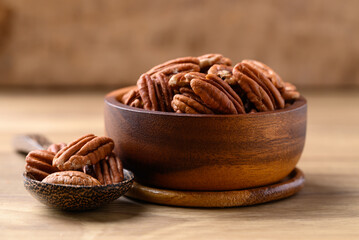 Raw peeled pecan nuts in wooden bowl on wooden background, Food ingredient